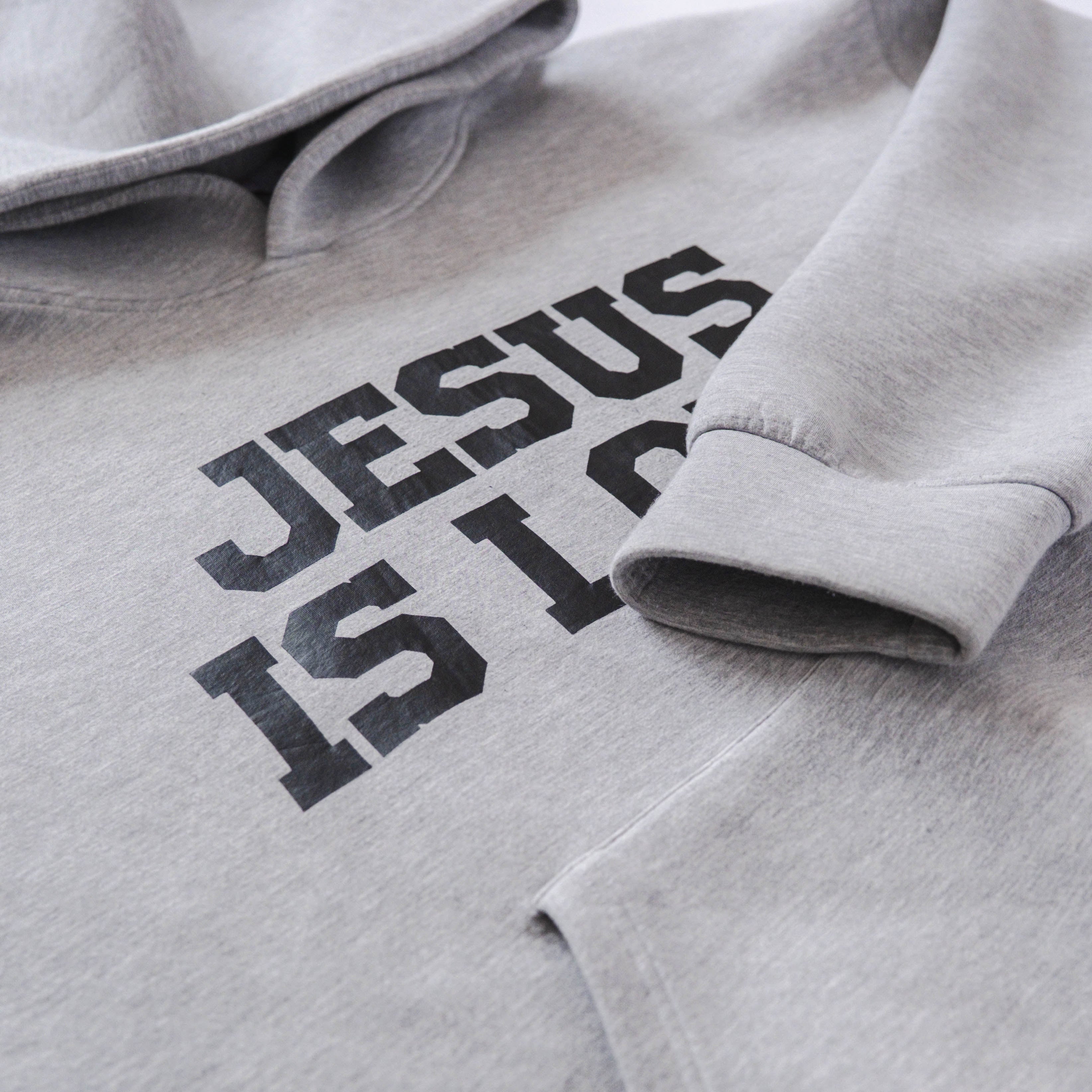 Gray hoodie with 'Jesus is Love' text on a light gray background